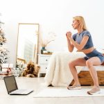 Woman exercising next to a Christmas tree.